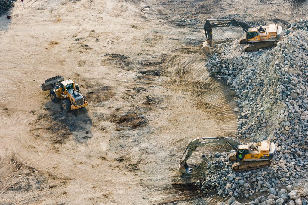 Panoramic view of a mining site showcasing hydraulic cylinders in the distance. The cylinders stand tall and are integrated into various mining machinery. They provide mechanical force and motion, enabling critical operations within the mining industry. The scale of the mining site can be observed, with the hydraulic cylinders serving as essential components amidst a sprawling landscape of excavation, transportation, and processing equipment. Their presence highlights the vital role they play in facilitating efficient and productive mining operations